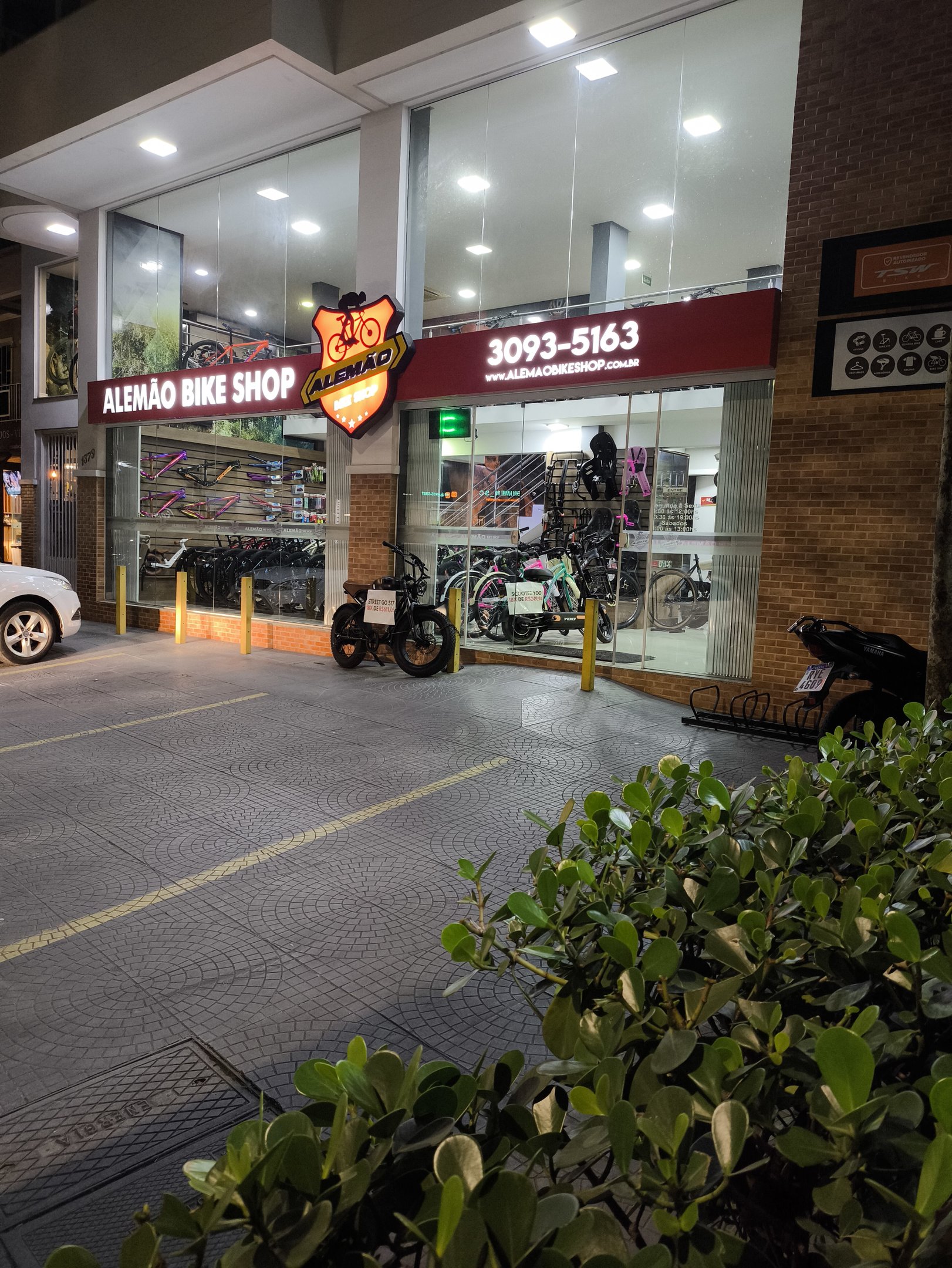 Fachada da Alem&atilde;o Bike Shop durante a noite